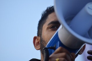 A student speaks into a megaphone Wednesday during the Sanctuary Campus walk out protest, which sought to send a message about Trump's rhetoric about women, minorities, immigrants, Muslims, etc...